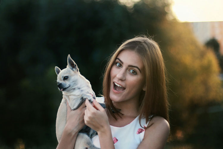 A Girl carrying a small dog.